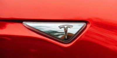 Tesla Brand Signage On A Red Sedan Car