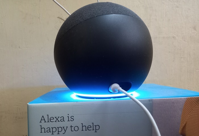 Alexa Echo speaker in listening mode with blue lights and cyan ring visible. 