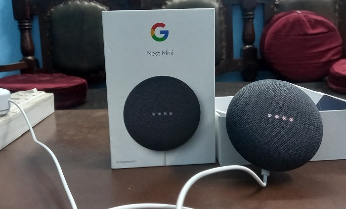 Google Nest Mini speaker in listening mode with white lights on.